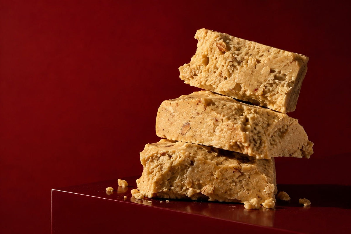 Piezas de turrón de Jijona apiladas sobre fondo granate