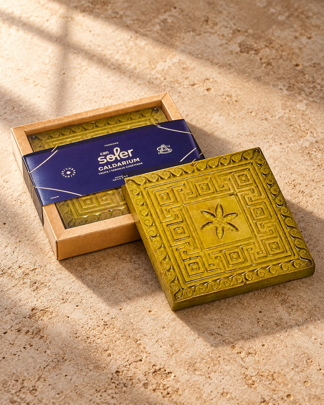 Chocolate de Museo Caldarium de Can Soler: tableta dorada con relieve de grecas junto a su caja con faja azul