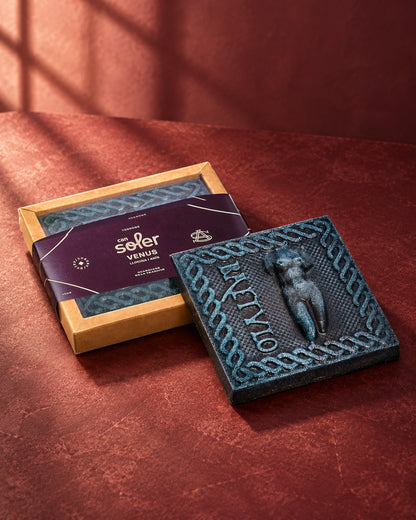 Caja de Chocolate de Museo Venus de Can Soler con faja morada junto a una placa de chocolate con el relieve de una Venus