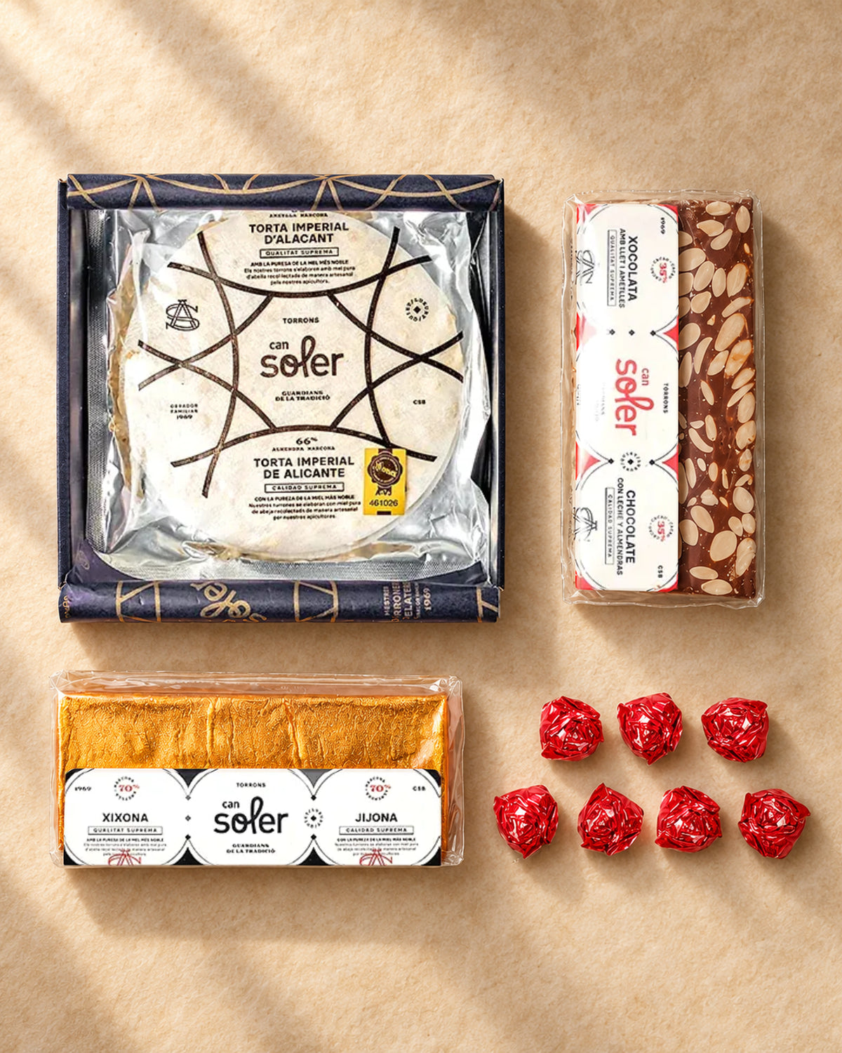 Lote «Detalle navideño» de Can Soler desde arriba: torta imperial de Alicante, turrón de chocolate, turrón de Jijona y bombones rojos