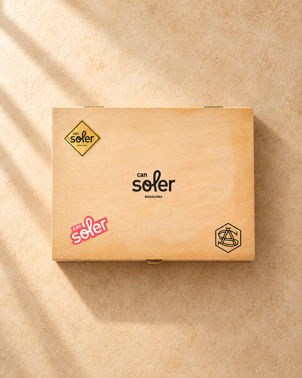 Caja de madera cerrada del lote «Lo más» con el logotipo de Can Soler en la tapa, vista desde arriba