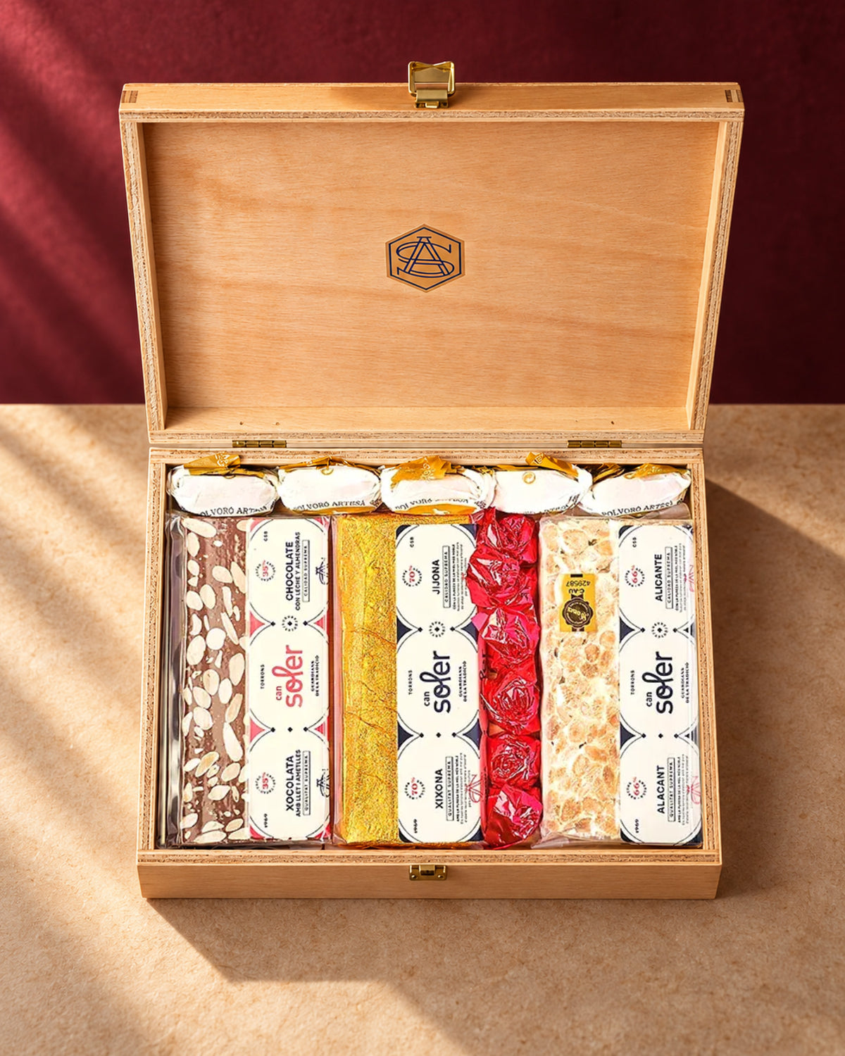 Lote de regalo «Para quedar bien» de Can Soler: caja de madera abierta con turrones variados, polvorones y dulces envueltos