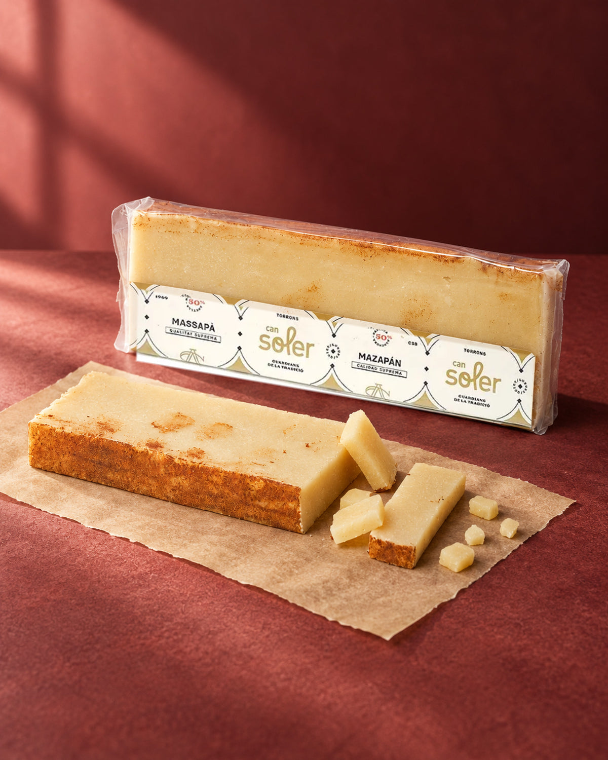Turrón de mazapán de Can Soler en su envase, con una barra de borde tostado y trozos cortados delante