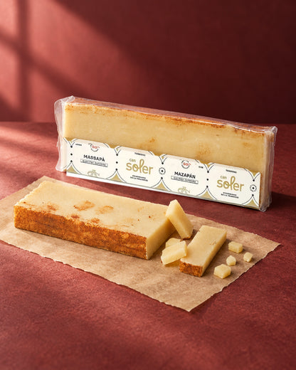 Turrón de mazapán de Can Soler en su envase, con una barra de borde tostado y trozos cortados delante