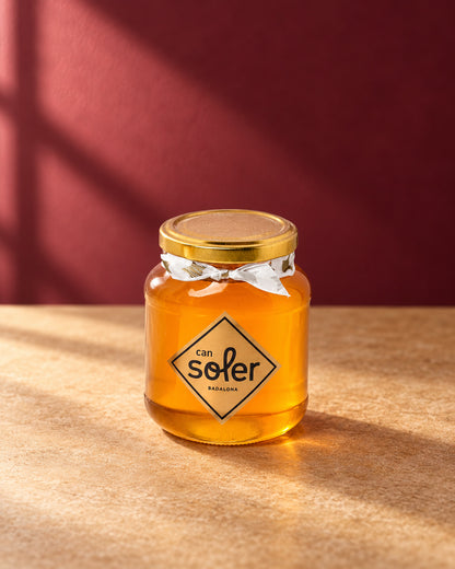 Tarro de cristal de miel natural de azahar Can Soler con tapa dorada, lazo y etiqueta romboidal de la marca