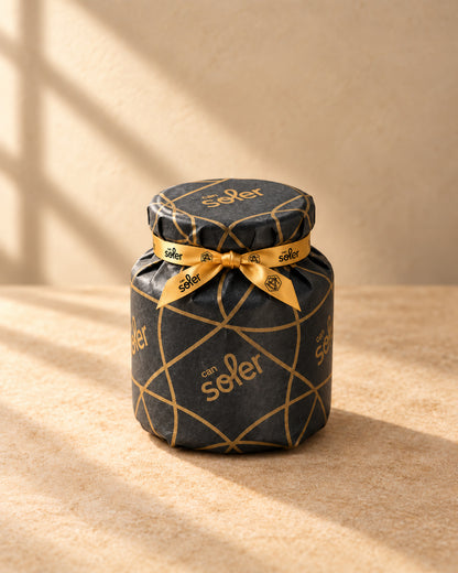 Tarro de miel natural de azahar de Can Soler envuelto para regalo en papel negro con dibujo dorado y cinta dorada