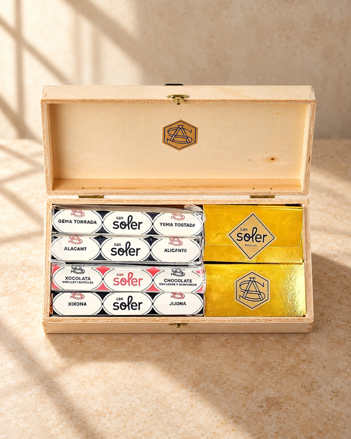 Pack degustación «Con 8 basta» de Can Soler: cofre de madera abierto con cuatro turrones y dos cajas doradas de la marca