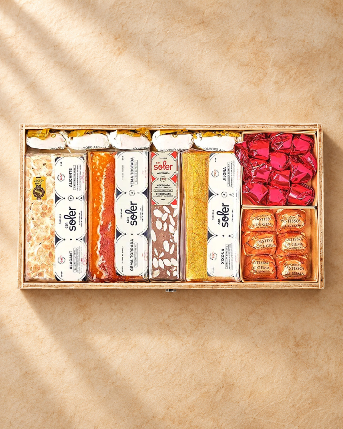 Vista desde arriba del pack degustación «Familia numerosa» de Can Soler: caja de madera con turrones y dulces variados