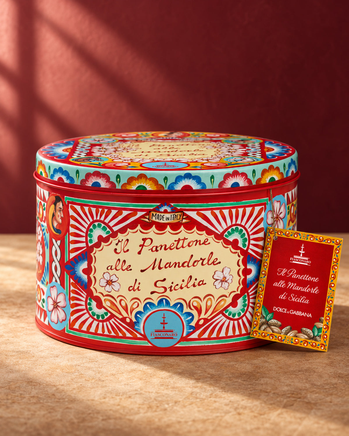 Lata redonda roja y turquesa del panettone Fiasconaro edición Dolce&Gabbana de almendra, con su etiqueta colgante roja