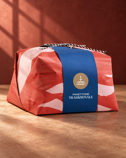 Panettone Fiasconaro tradicional en su envoltorio de papel rojo y rosa con faja azul y lazo de cordón