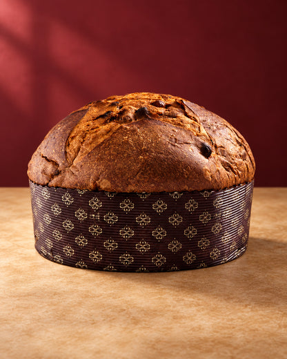Panettone Fiasconaro tradicional entero en su molde de papel marrón, con la corteza tostada y agrietada