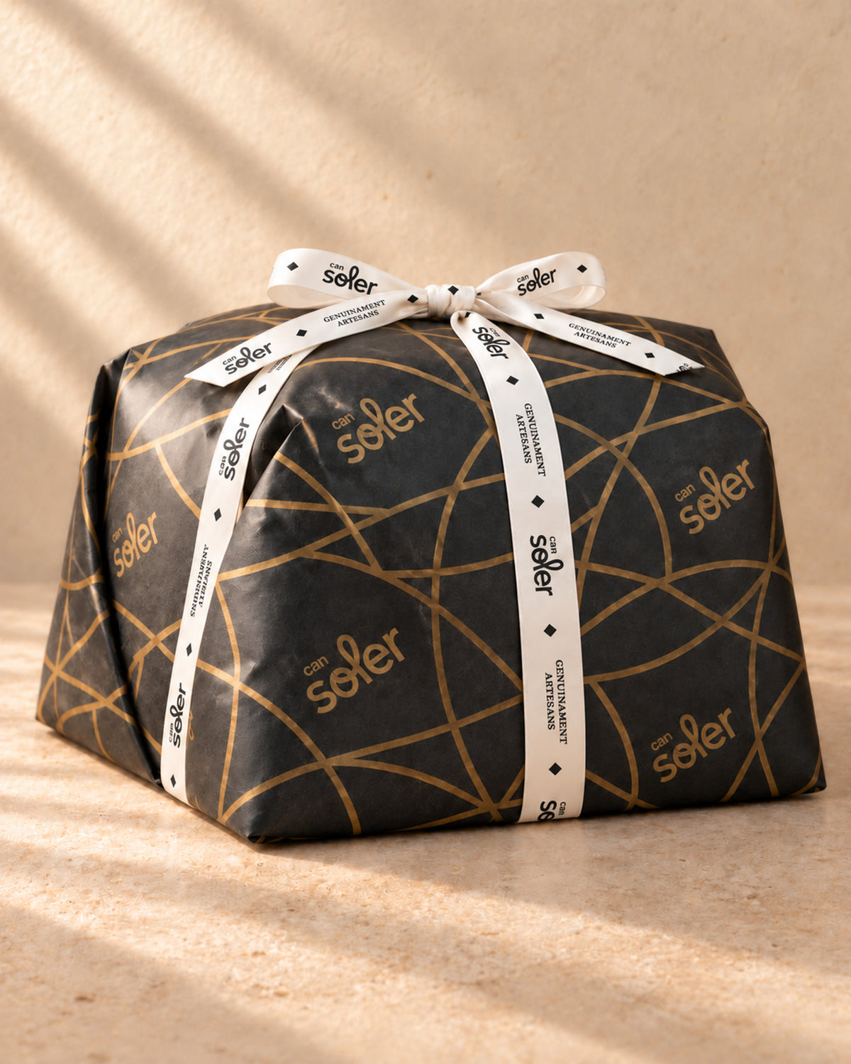 Panettone Fiasconaro tradicional envuelto para regalo en el papel negro y dorado de Can Soler con cinta blanca