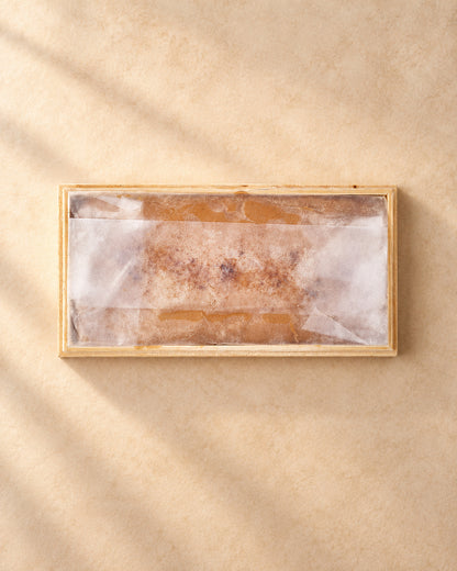 Caja de madera abierta con turrón de Jijona a la piedra cubierto por papel translúcido, vista desde arriba