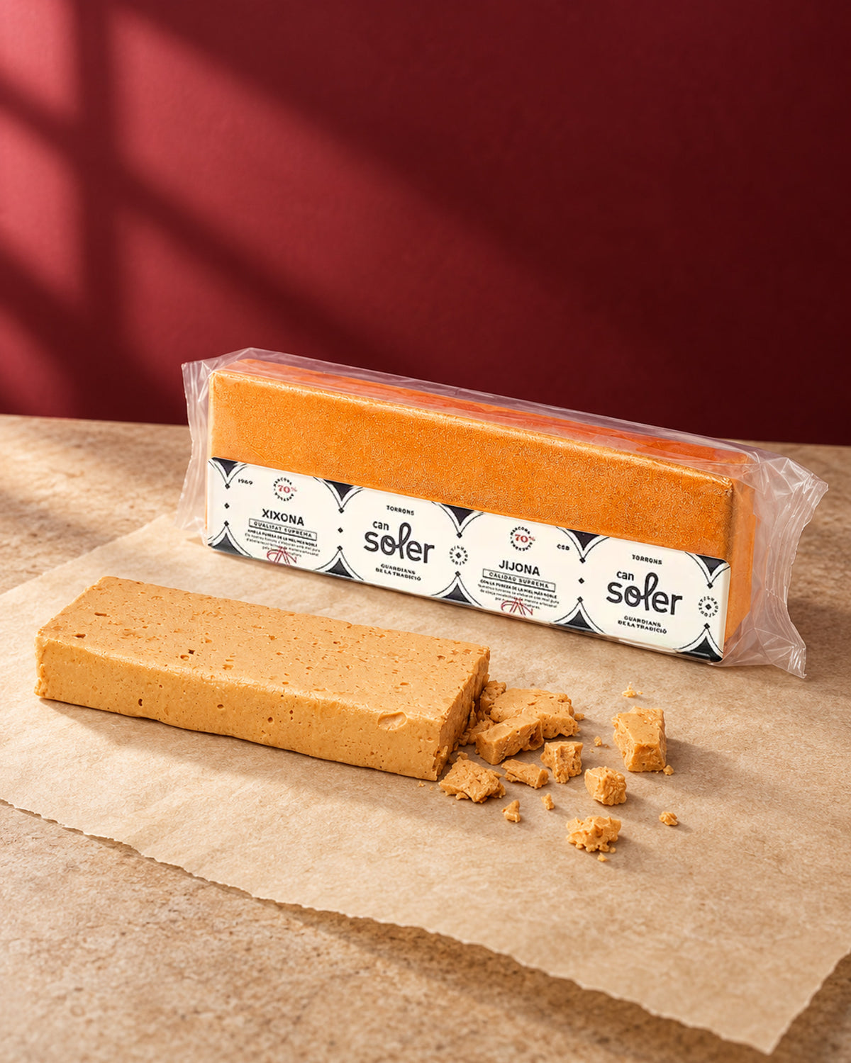 Turrón de Jijona D.O. Jijona de Can Soler en su envase, con una barra cortada sobre papel