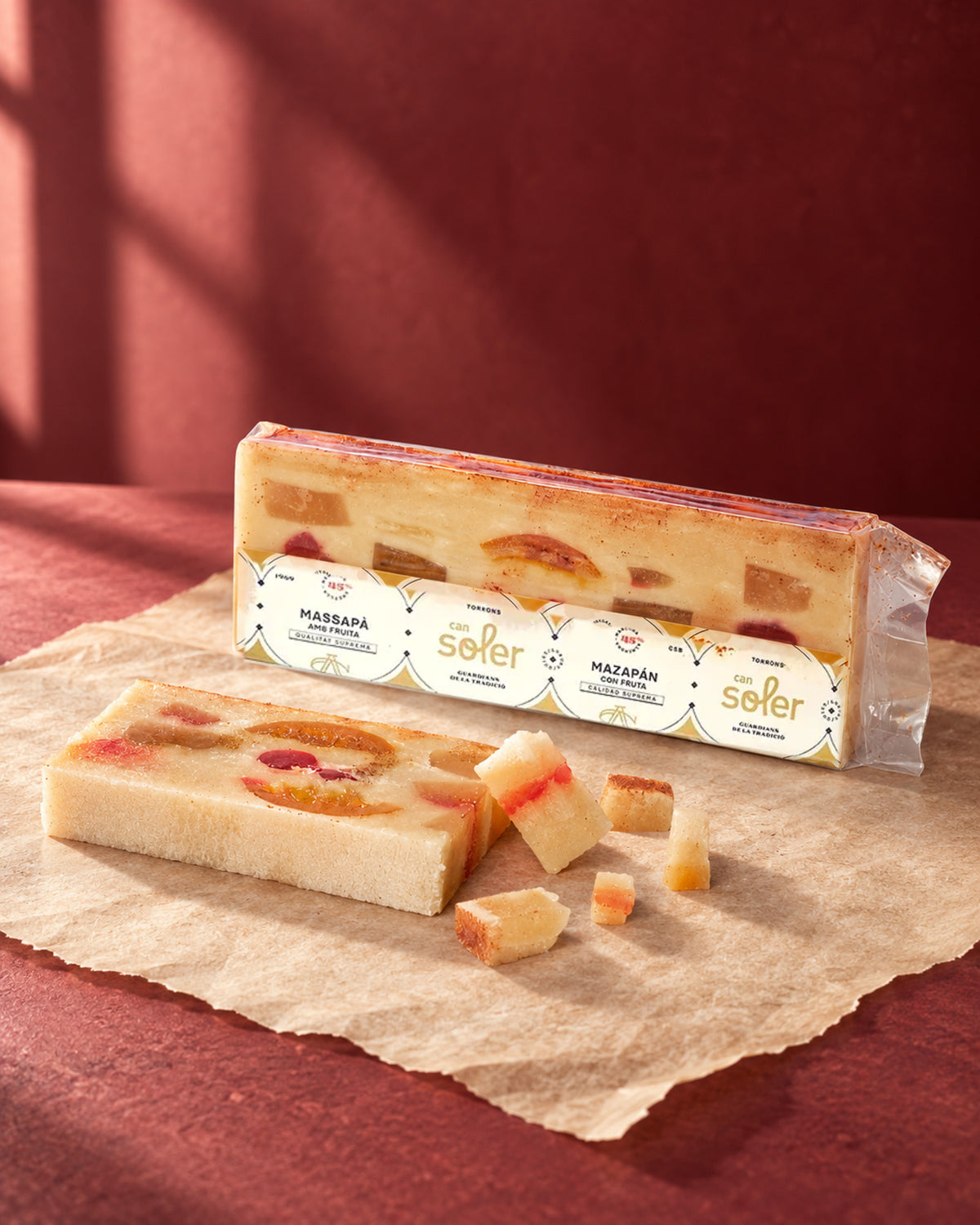 Turrón de mazapán con fruta de Can Soler en su envase, con una barra sin envase y dados cortados delante