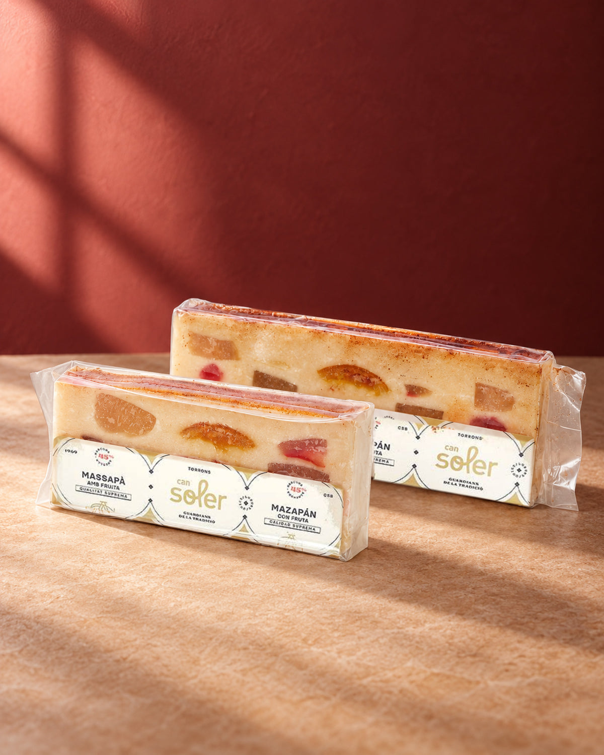 Dos tamaños de turrón de mazapán con fruta de Can Soler en envase transparente, con la fruta confitada a la vista