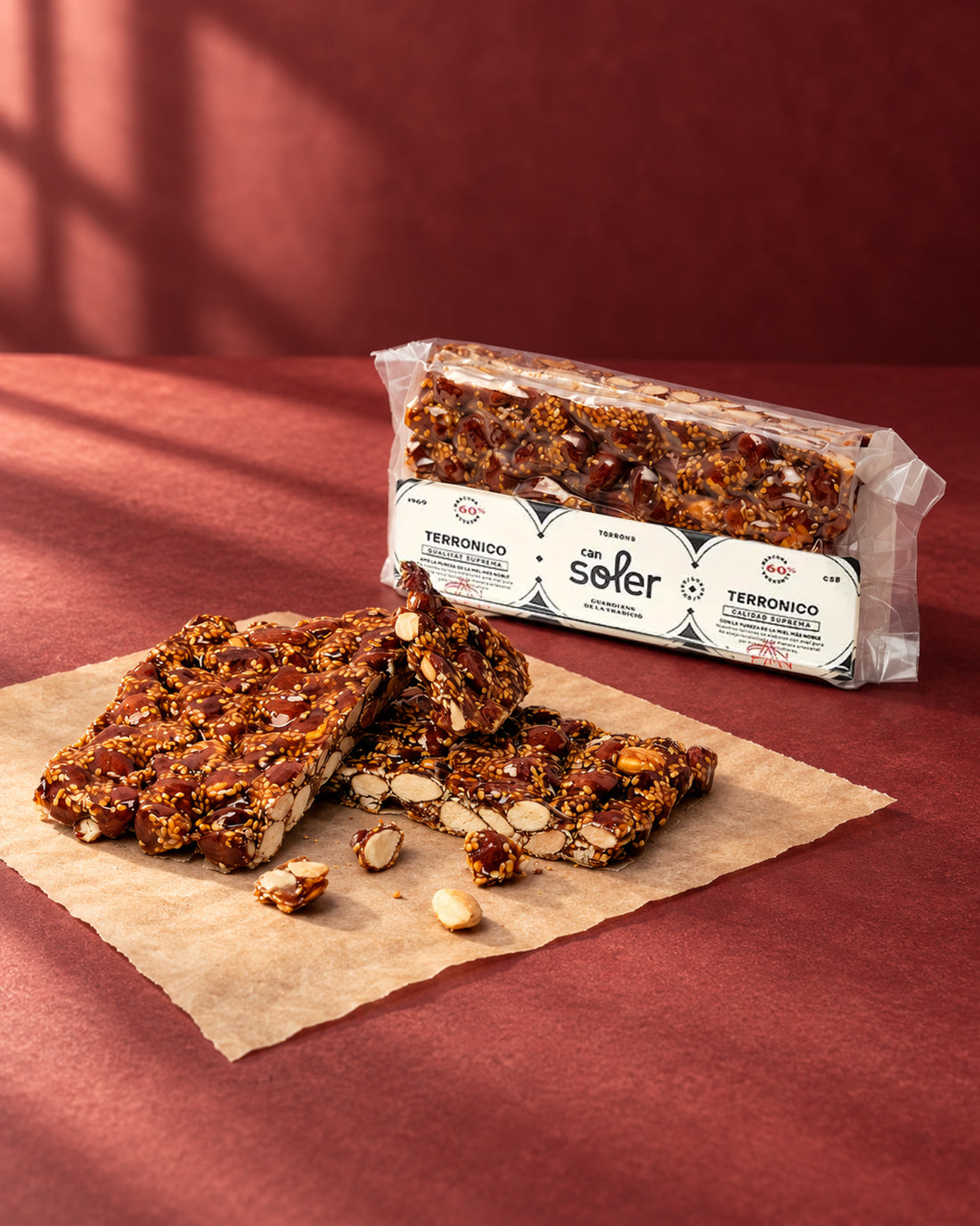 Turrón «Terronico» de Can Soler: placa partida en trozos con almendras caramelizadas y el paquete con etiqueta detrás