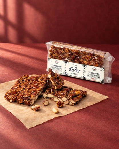 Turrón «Terronico» de Can Soler: placa partida en trozos con almendras caramelizadas y el paquete con etiqueta detrás