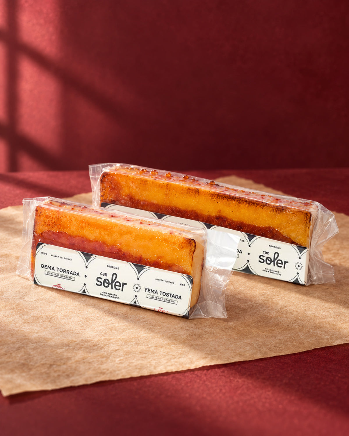 Dos tamaños de turrón de yema tostada de Can Soler en envase transparente, con la capa tostada a la vista